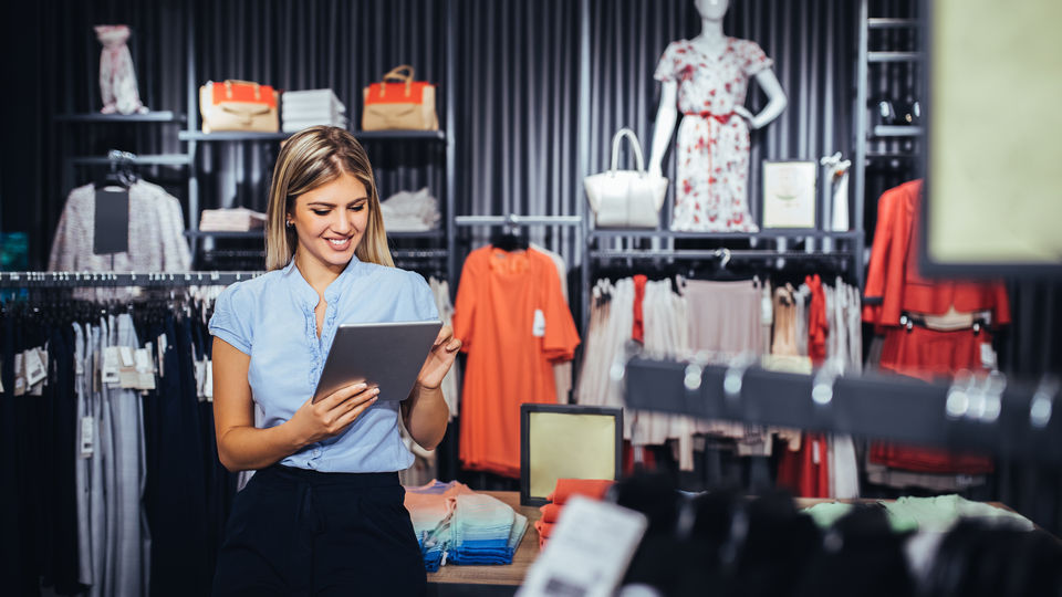 female sales associate with tablet device in retail apparel store