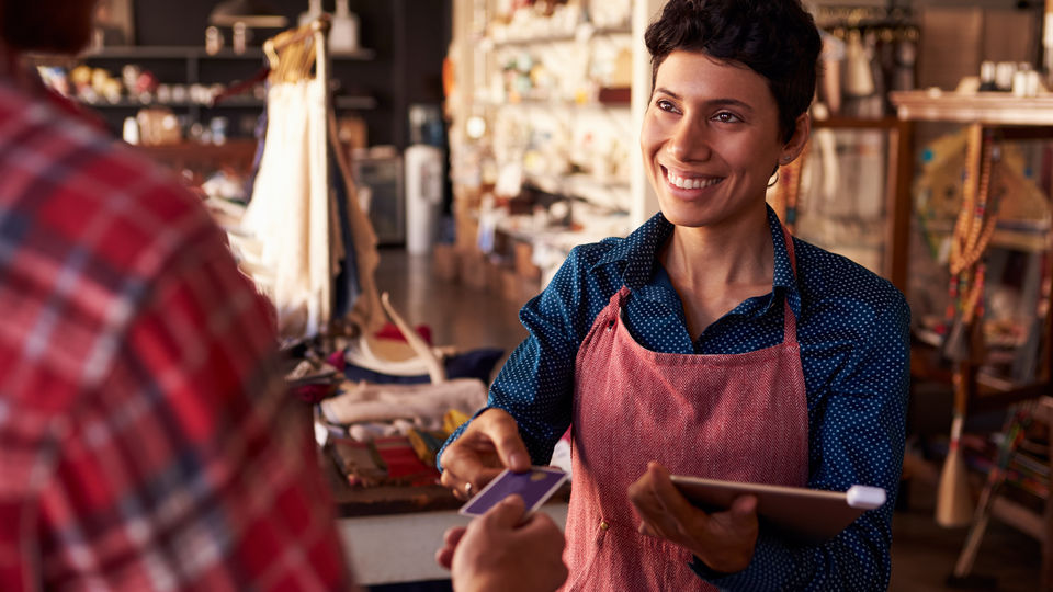 retail sales associate with credit card reader on digital tablet accepting payment from customer