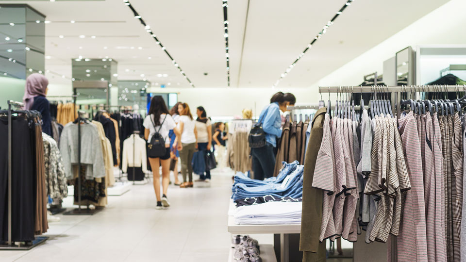 aisle in retail apparel store with groups and single shoppers inspecting the merchandise