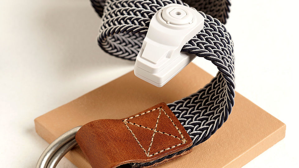 leather and braided fabric belt coiled and carrying an infuzion hard tag in retail accessories store