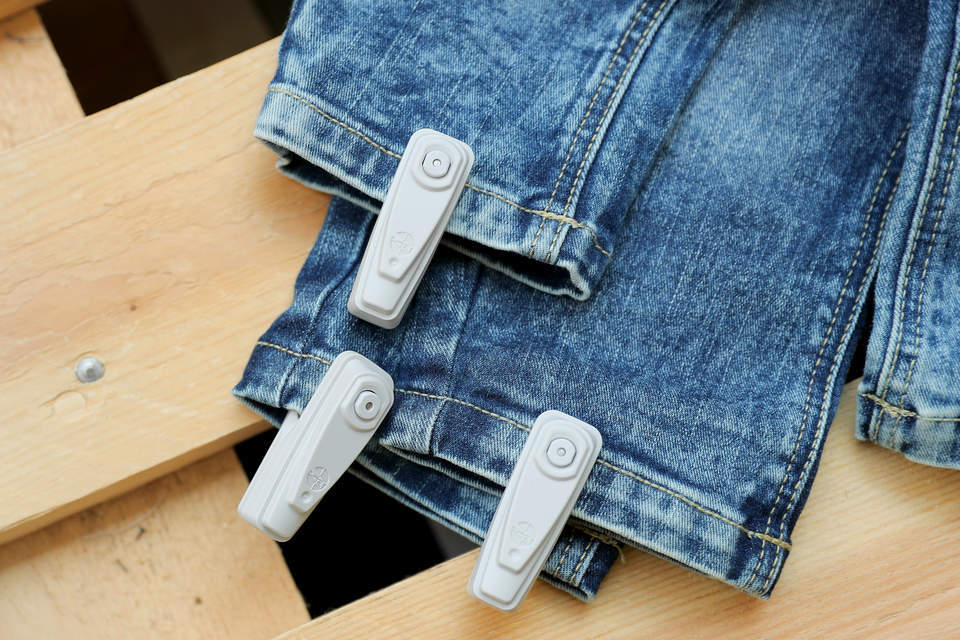 retail apparel store wood display table with several pairs of jeans carrying infuzion hard tags