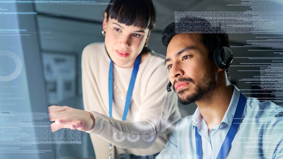 man and woman data analysts reviewing screen of retail data overlaid by lines and blocks of computer code