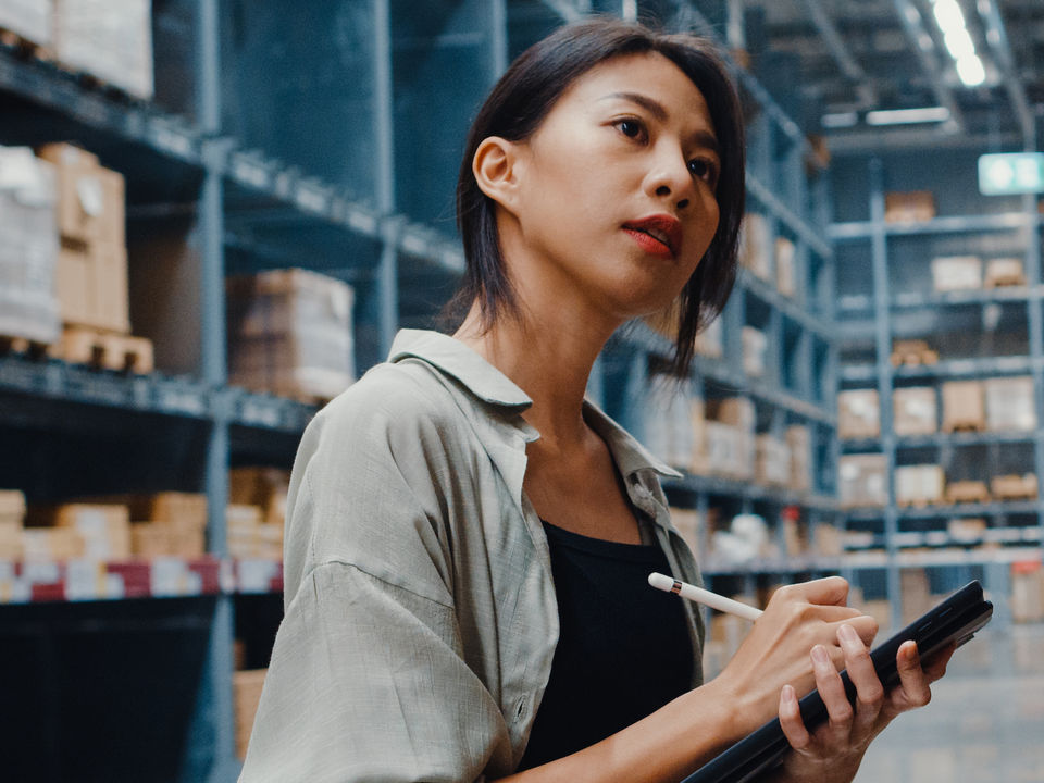 woman in retail warehouse entering inventory information with stylus on tablet device