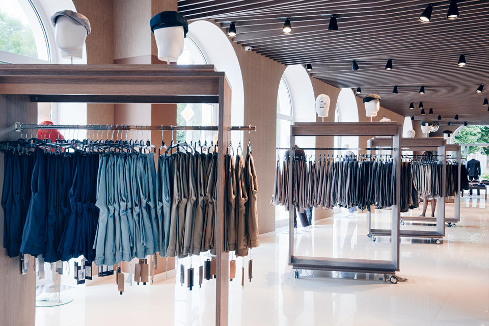 interior of bright modern retail apparel store displaying racks of clothing in front of large windows