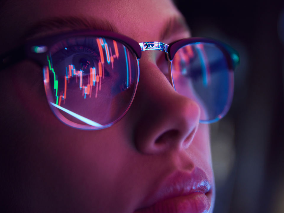 close-up face of woman retail store employee with computer grahic data reflected in her eyeglasses