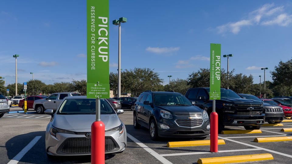 several vehicles in a retail store parking lot in spots reserved for package pickup