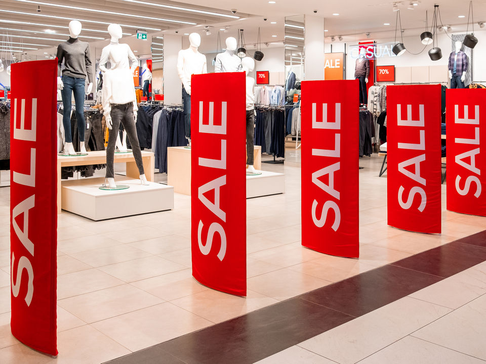 retail apparel store entrance with sale banners on loss prevention pedestals