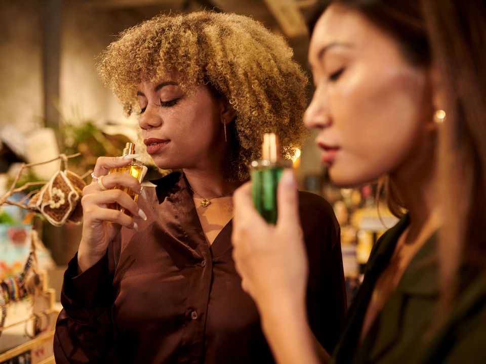 closeup of two female shoppers eyes closed sniffing perfume scents in retail health beauty aids store