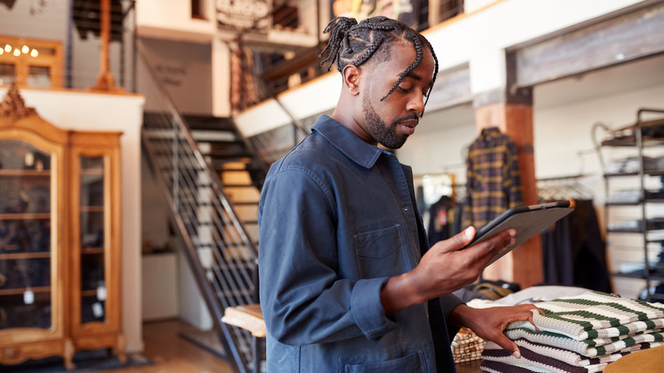 male retail apparel store manager reviewing store information on tablet