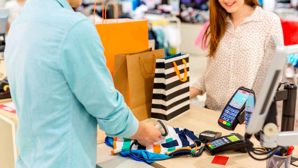 retail apparel store customer ringing up his purchases using self-checkout kiosk
