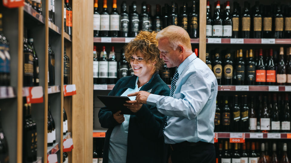 male and female retail associates reviewing store operations on electronic device