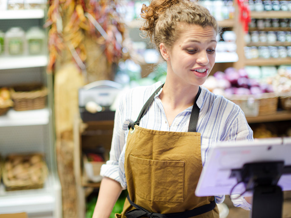 woman in retail store uniform ringing up customer at point of sale cashwrap