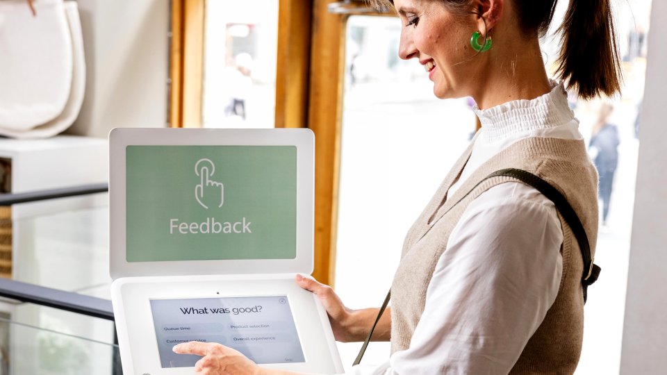 female shopper looking at happyornot tablet device in brightly lit retail store