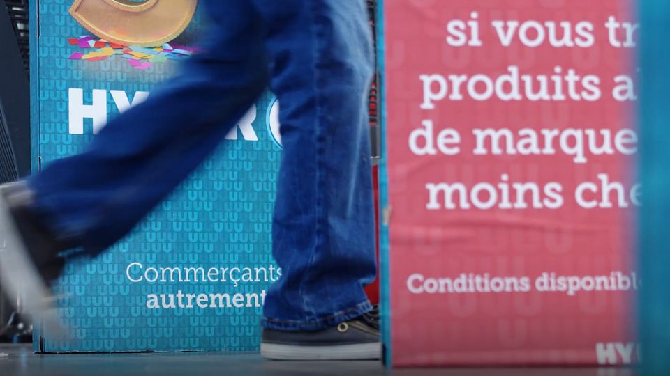 person walking past entrance signs at hyper-u retail store