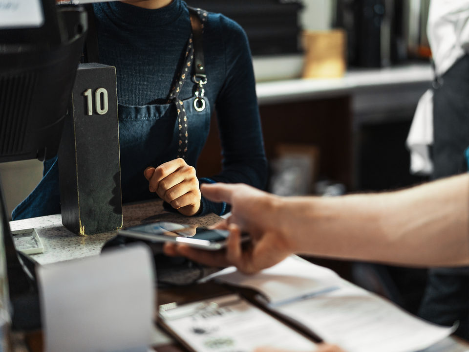 store employee helps customer pay with cell phone at point of sale cashwrap