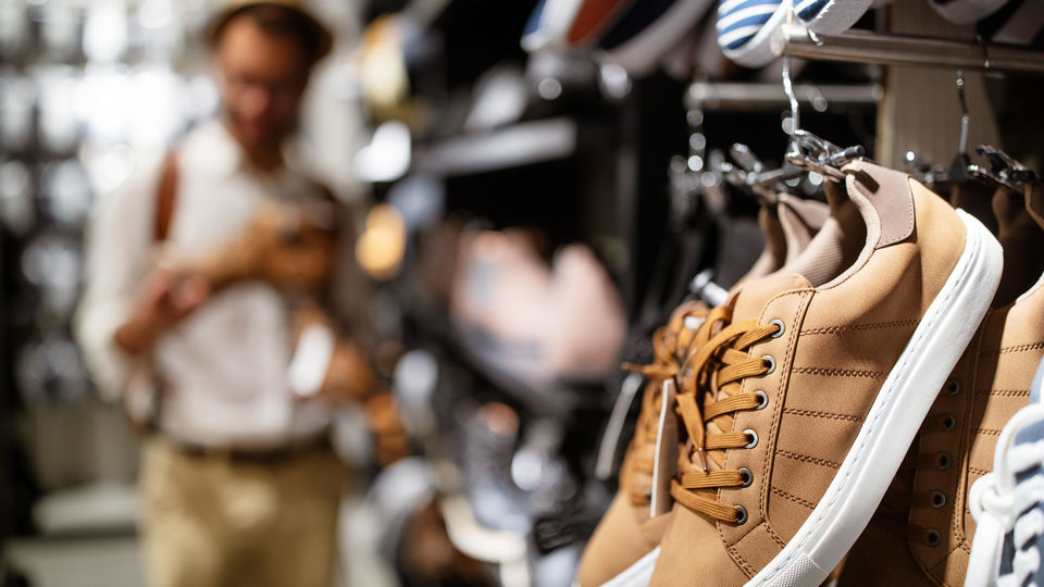 athletic shoes on wall display in retail footwear store with male customer in background