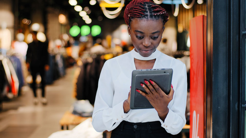 woman store manager reviewing store data on electronic tablet advice at front entrance of apparel store