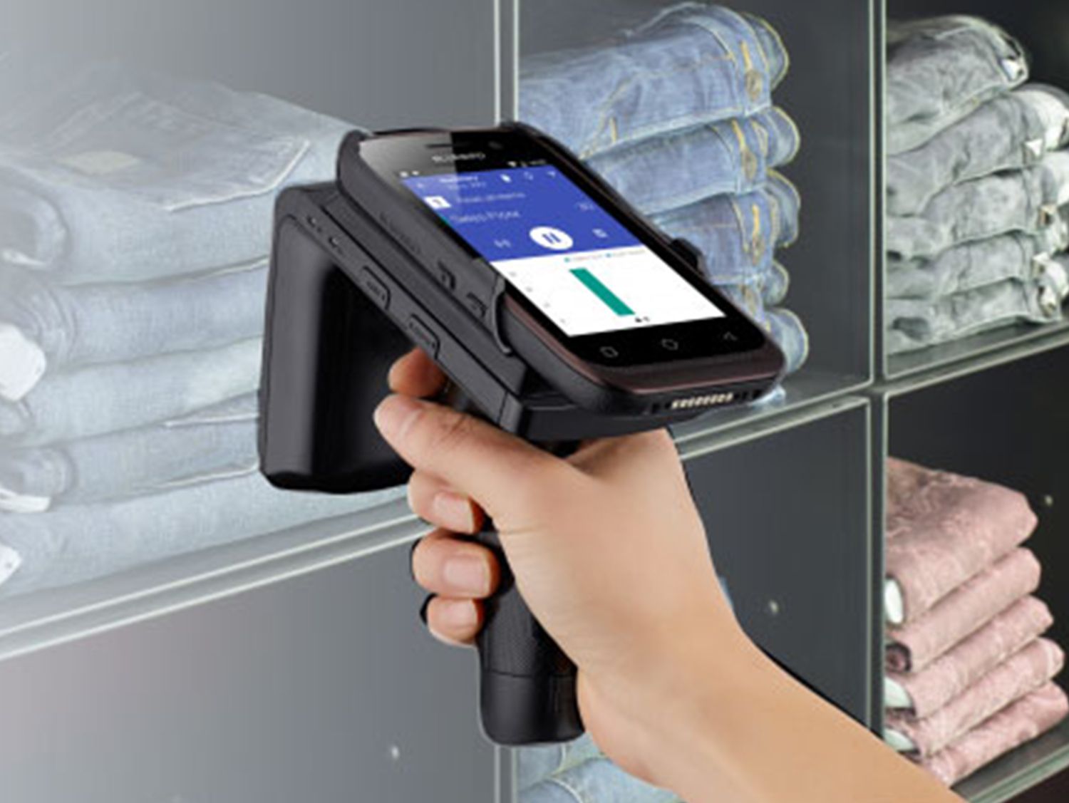 Retail associate using inventory scanner at shelf of jeans