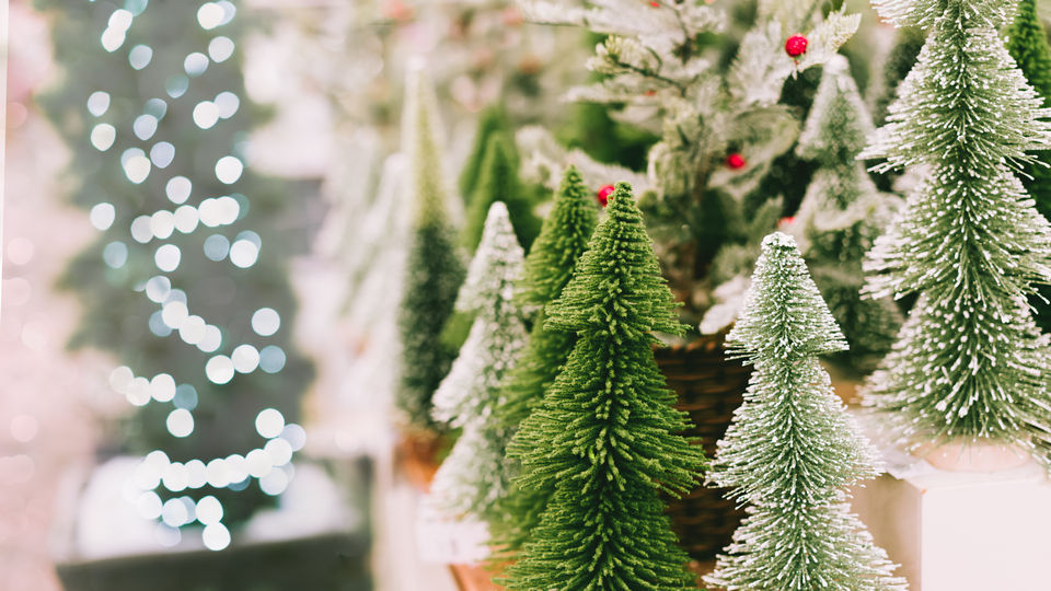 store display of multiple toy christmas trees with snow and holiday lights and decorations