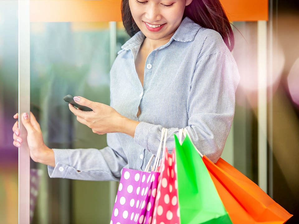 female customer carrying colorful shopping bags entering or leaving a retail store