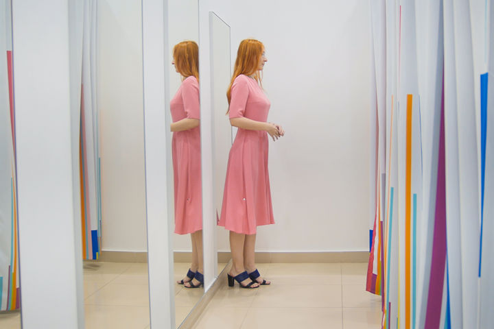 donna parzialmente riflessa negli specchi del camerino a figura intera