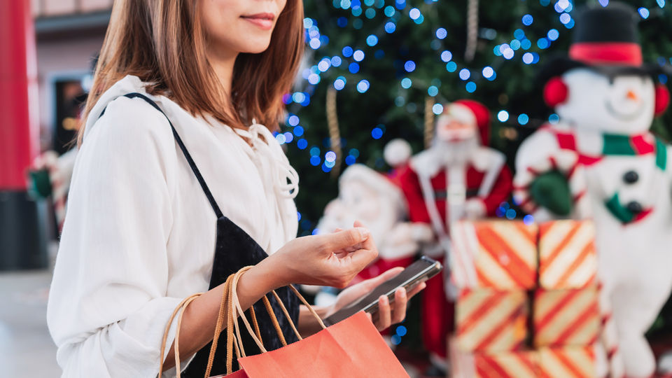 female shopper in holiday decorated retail shopping mall carrying shopping bags