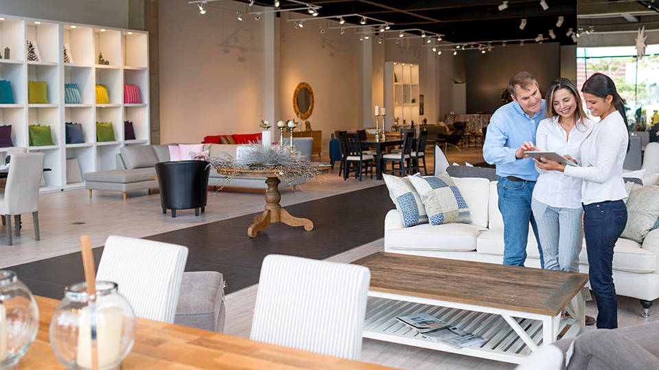 man and woman shoppers in retail home furnishings store reviewing information on sales assitants tablet