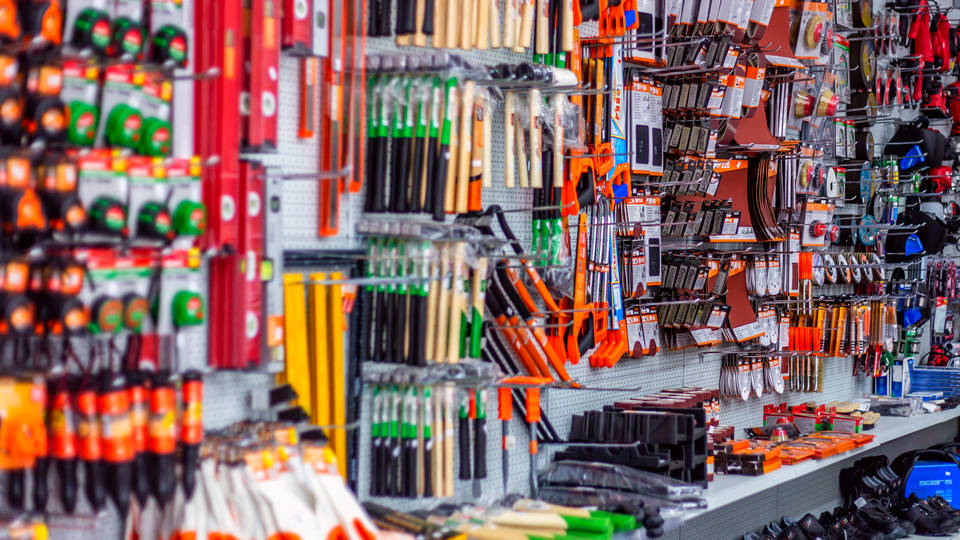 multi-colored household workshop tools hanging on wall display in retail diy hardware store