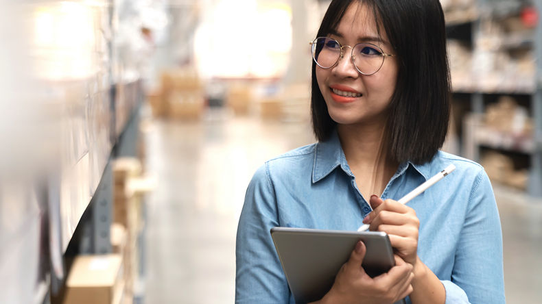 female warehouse worker with tablet inspecting shelved items